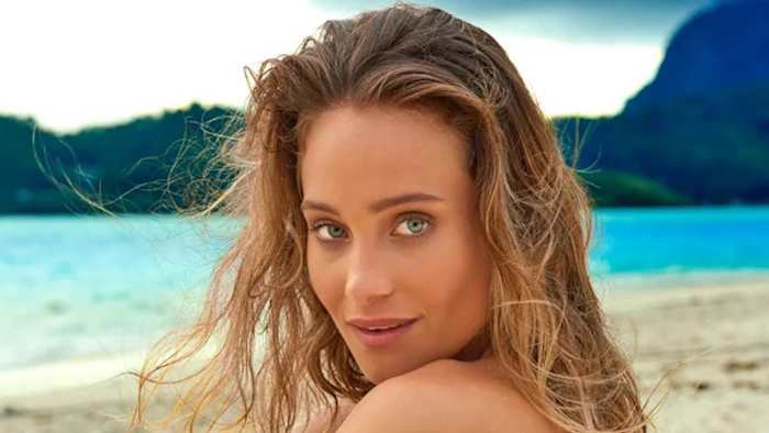 Hannah Jeter sits on the beach and looks to her side at the camera.